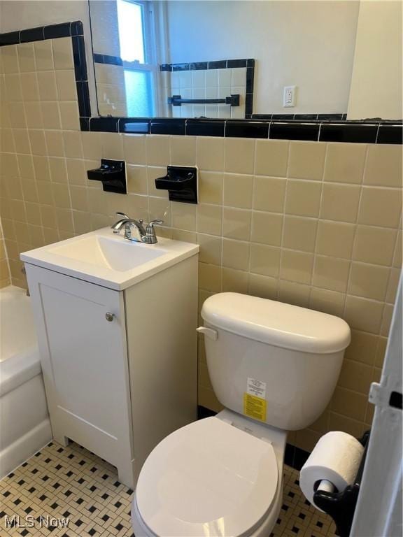 full bathroom featuring tile walls, toilet, tile patterned floors, and a washtub