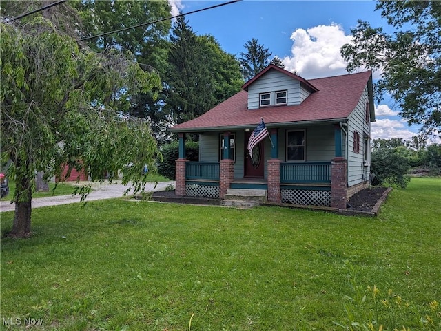 view of front of house featuring covered porch, a shingled roof, and a front lawn