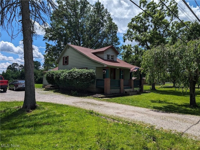 view of front of home with covered porch, driveway, and a front lawn