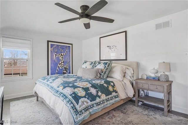 bedroom with visible vents, a ceiling fan, baseboards, and wood finished floors