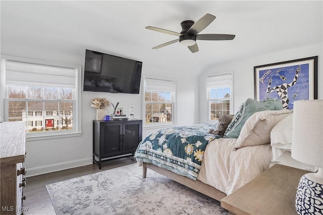 bedroom featuring multiple windows, a ceiling fan, baseboards, and wood finished floors