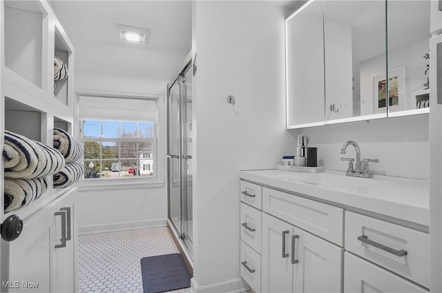 full bathroom with a stall shower, vanity, and baseboards