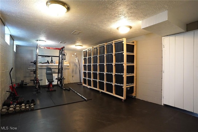 exercise area with a textured ceiling and concrete block wall