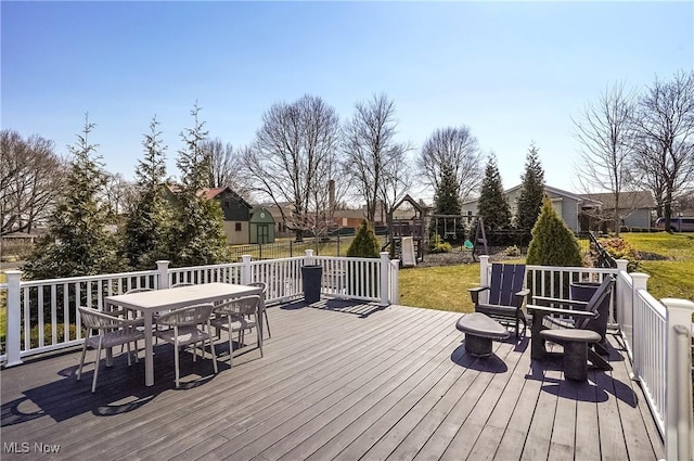 wooden deck featuring outdoor dining area and a yard