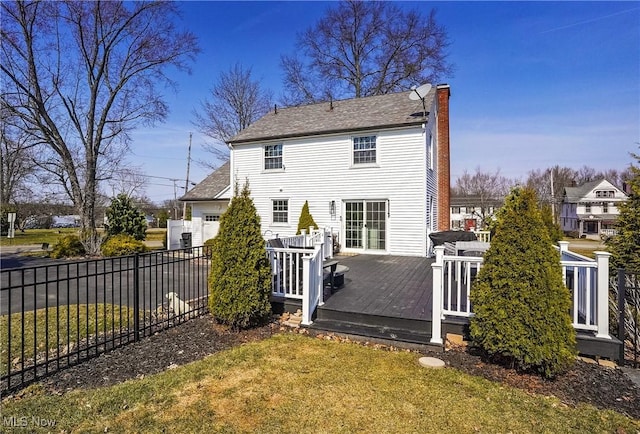 back of property with fence, driveway, a wooden deck, a yard, and a chimney