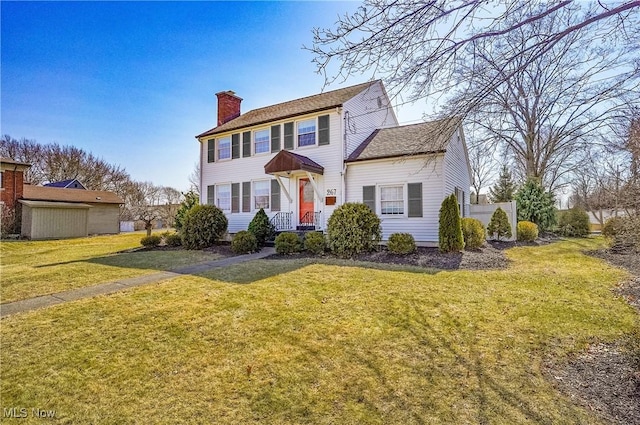 colonial inspired home with a chimney and a front yard