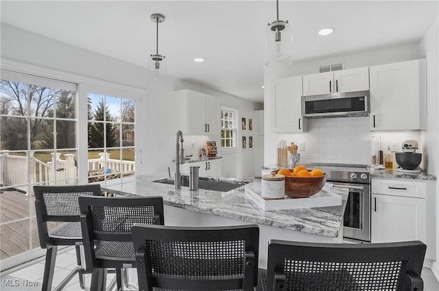 kitchen with tasteful backsplash, visible vents, appliances with stainless steel finishes, white cabinets, and a sink