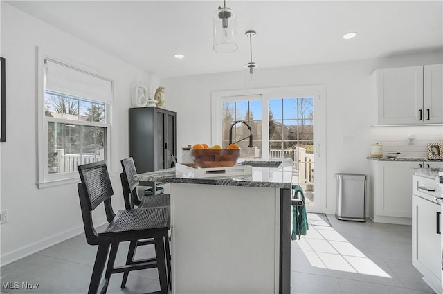 kitchen featuring a sink, light stone countertops, a kitchen island, and light tile patterned flooring