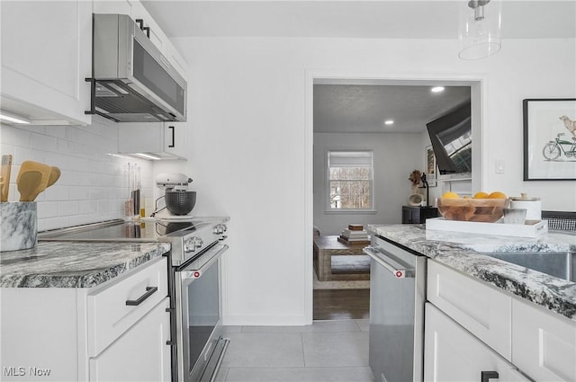 kitchen with tile patterned floors, white cabinets, light stone countertops, and appliances with stainless steel finishes