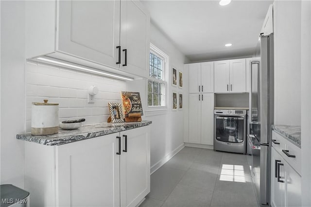 kitchen featuring oven, light stone counters, tasteful backsplash, white cabinetry, and light tile patterned floors