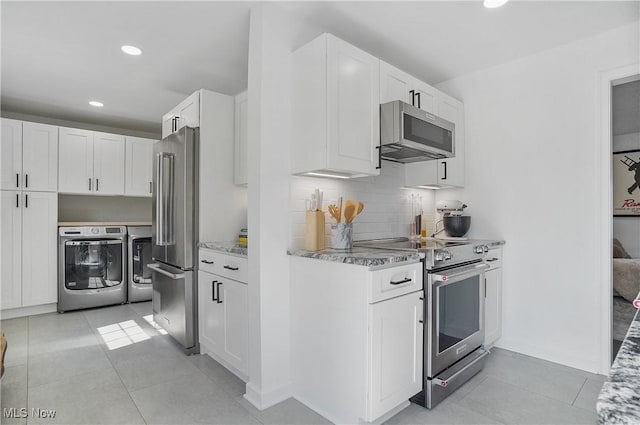 kitchen featuring washing machine and clothes dryer, light tile patterned floors, white cabinets, and appliances with stainless steel finishes