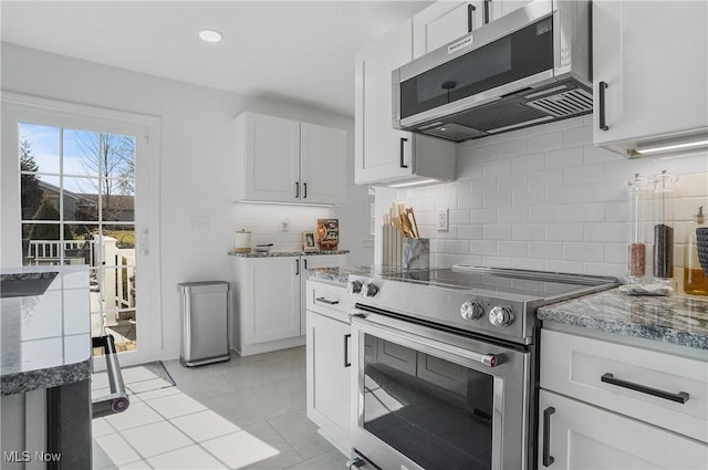 kitchen featuring tasteful backsplash, white cabinetry, appliances with stainless steel finishes, light tile patterned flooring, and light stone countertops