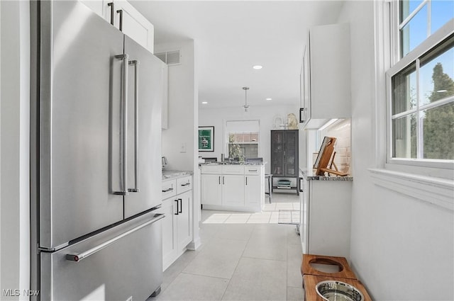 kitchen with white cabinets, light tile patterned floors, visible vents, and high end refrigerator