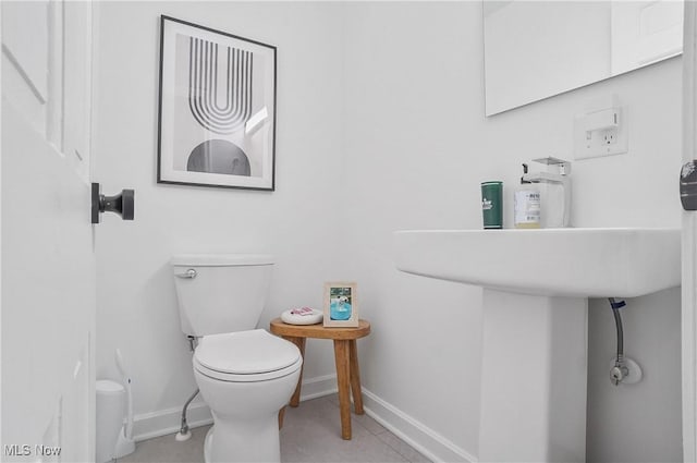 half bathroom featuring tile patterned flooring, toilet, and baseboards