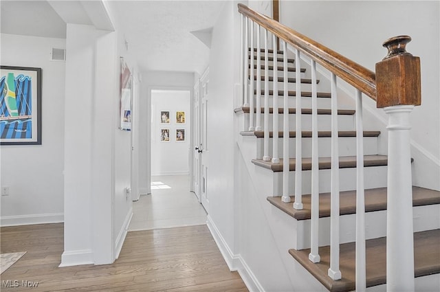 stairway featuring wood finished floors and baseboards