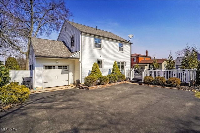 exterior space featuring fence, a wooden deck, an attached garage, central AC, and aphalt driveway