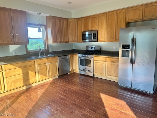 17583 Davis Ridge Rd, Caldwell, OH 43724 - kitchen with stainless steel appliances, a sink, dark wood-style flooring, dark countertops, and pendant lighting