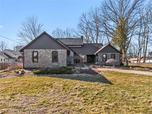 view of front of home featuring stone siding, a chimney, a front yard, and fence