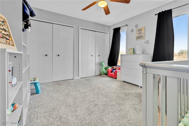 bedroom with multiple windows, speckled floor, two closets, and ceiling fan