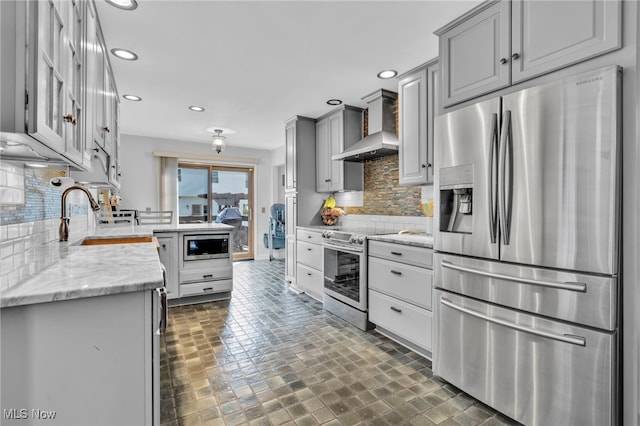 kitchen with backsplash, wall chimney range hood, recessed lighting, gray cabinets, and stainless steel appliances