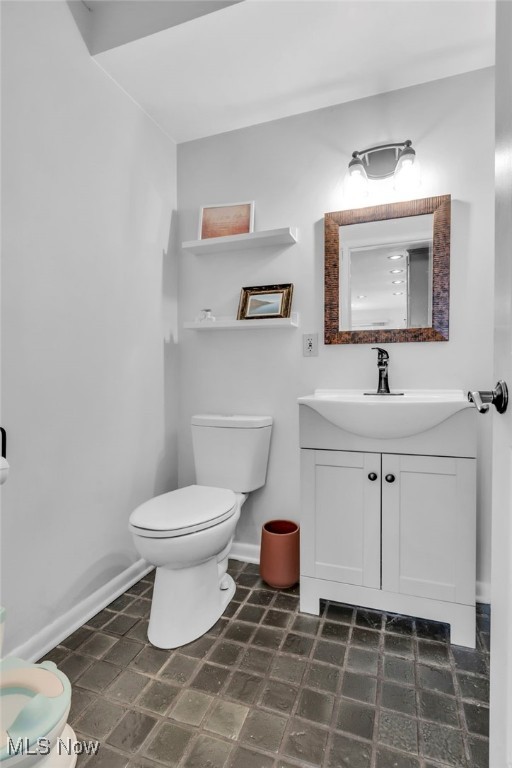 bathroom with toilet, vanity, and baseboards