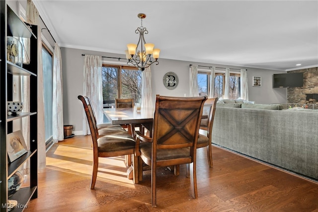 dining space featuring a wealth of natural light, a chandelier, crown molding, and wood finished floors