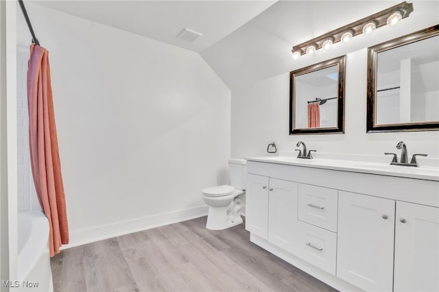 full bath with visible vents, toilet, a sink, wood finished floors, and vaulted ceiling