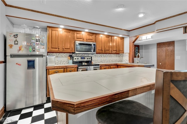 kitchen featuring ornamental molding, appliances with stainless steel finishes, light countertops, decorative backsplash, and light floors