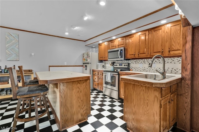 kitchen featuring a sink, a kitchen island, stainless steel appliances, crown molding, and light floors