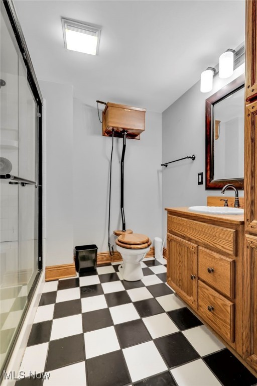 bathroom with tile patterned floors, a shower stall, toilet, and vanity