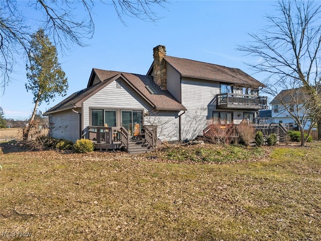 back of property with a wooden deck, a balcony, a lawn, and a chimney