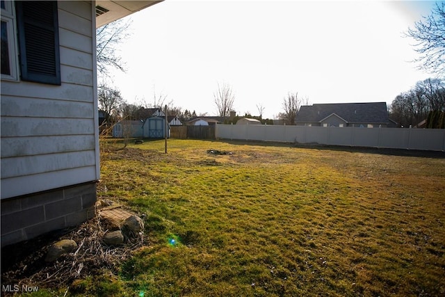 view of yard featuring an outbuilding, a storage shed, and fence