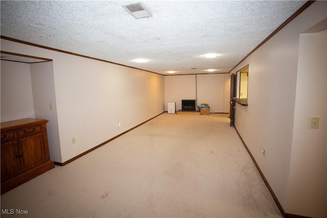 finished below grade area with visible vents, light colored carpet, ornamental molding, and a textured ceiling