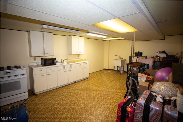 kitchen with light countertops, white range with gas stovetop, light floors, and a sink