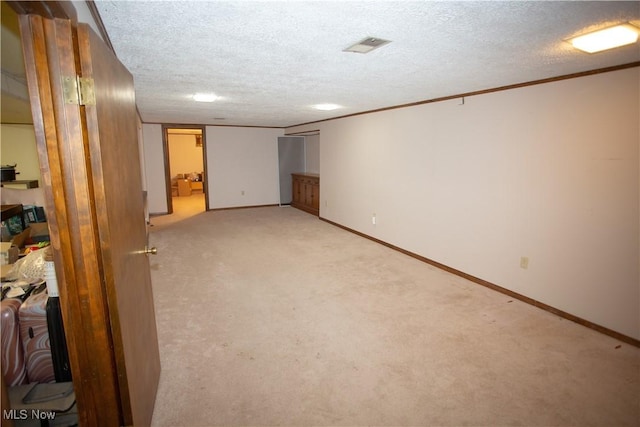 finished below grade area featuring baseboards, light carpet, a textured ceiling, and crown molding