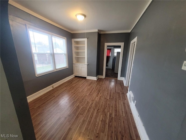 unfurnished bedroom featuring visible vents, baseboards, dark wood-style flooring, and ornamental molding