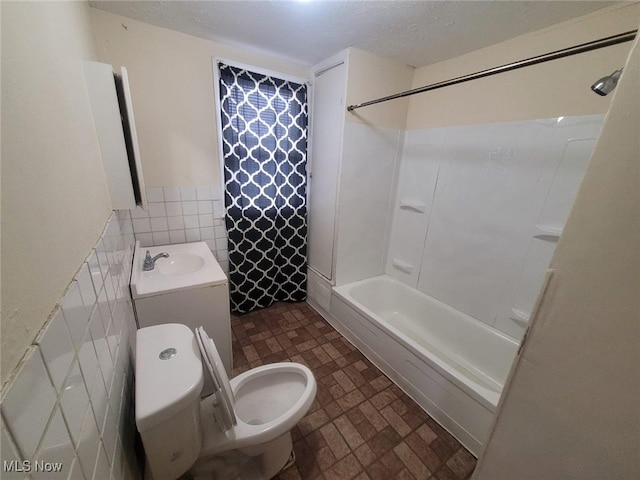 full bathroom with tile walls, toilet, shower / tub combination, wainscoting, and a textured ceiling