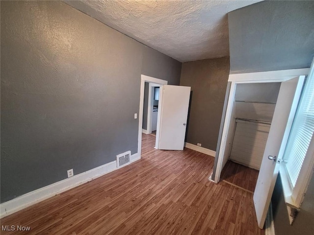 unfurnished bedroom with visible vents, baseboards, wood finished floors, a closet, and a textured ceiling