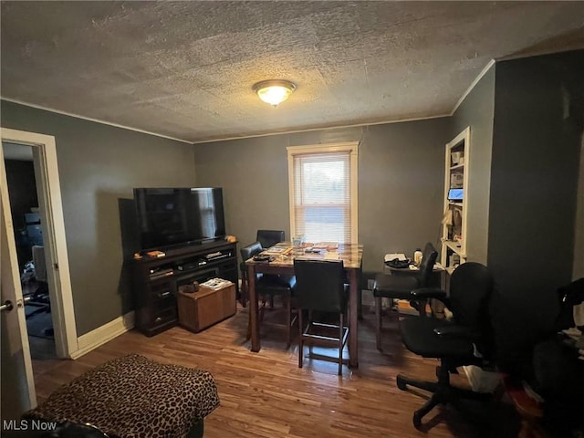 office area with a textured ceiling, wood finished floors, baseboards, and ornamental molding