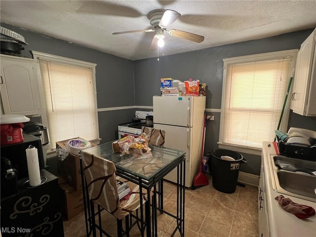 kitchen featuring range with gas cooktop, a sink, freestanding refrigerator, and a textured ceiling