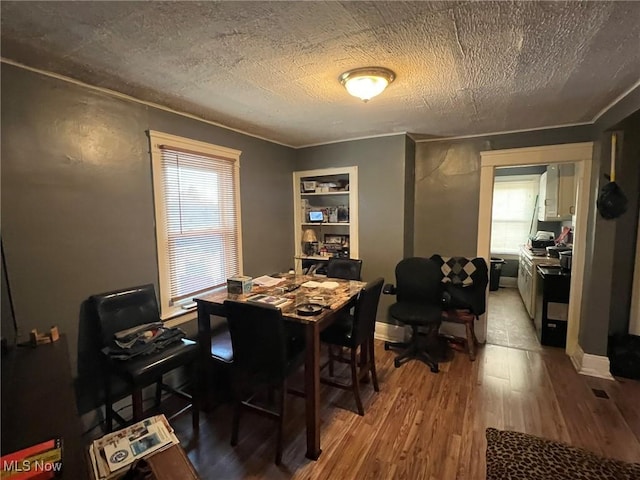 dining area with wood finished floors, baseboards, and a textured ceiling