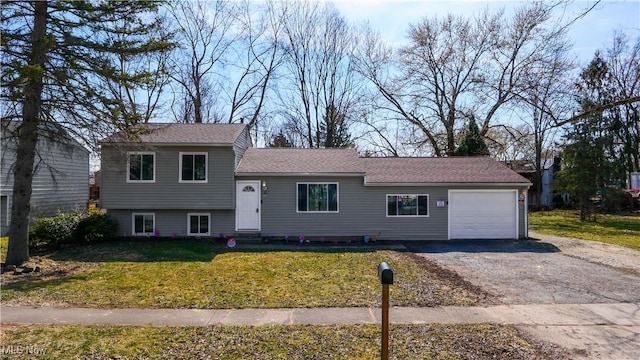 split level home with aphalt driveway, a front lawn, and a garage