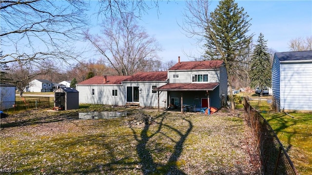 rear view of house featuring entry steps, a storage shed, an outbuilding, and fence