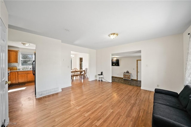 living area featuring visible vents, light wood-type flooring, and baseboards