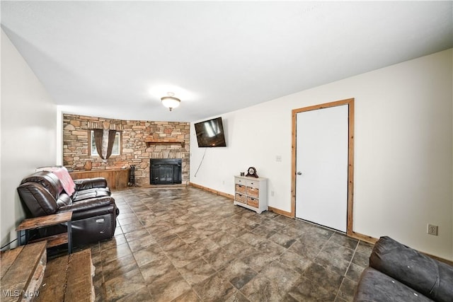 living area featuring a stone fireplace and baseboards