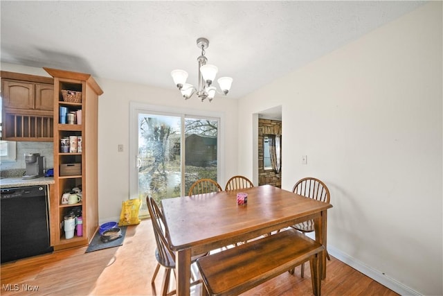 dining space featuring light wood-type flooring, baseboards, and a notable chandelier