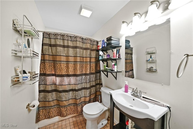 bathroom featuring toilet, a shower with shower curtain, and a sink