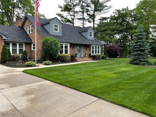 cape cod house with brick siding, a shingled roof, and a front lawn