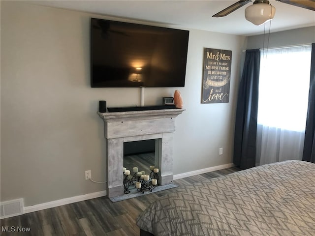 unfurnished bedroom with a ceiling fan, wood finished floors, visible vents, baseboards, and a fireplace