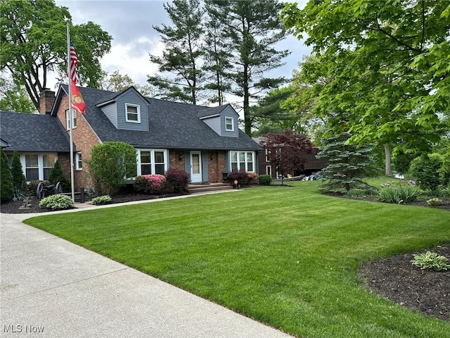 cape cod home featuring a front lawn, brick siding, and roof with shingles